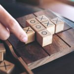 Closeup image of people playing wooden Tic Tac Toe game or OX game