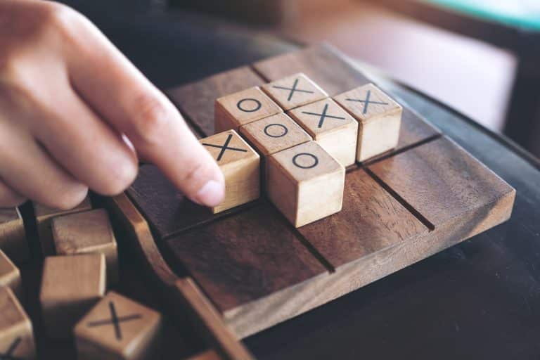 Closeup image of people playing wooden Tic Tac Toe game or OX game